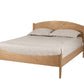A light oak wood bed frame with a curved headboard and footboard, shown with a beige sheet and two pillows on a solid white background.