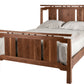 A wooden bed frame with a slatted headboard and footboard, shown with white bedding and pillows on a plain white background.