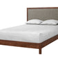 A modern wooden bed frame with a dark brown wood base and headboard, featuring a light gray upholstered panel on the headboard and styled with white bedding and two pillows, shown on a solid white background.