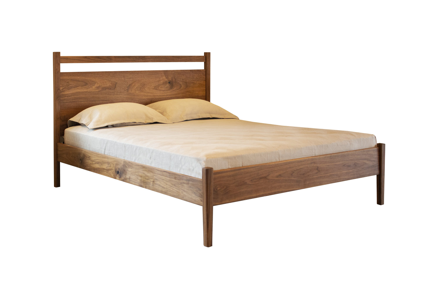 A modern Walnut wooden bed frame with a headboard and footboard, styled with a mattress and two pillows, shown on a plain white background.