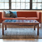 Brown leather sofa with patterned cushions in a room with large windows.