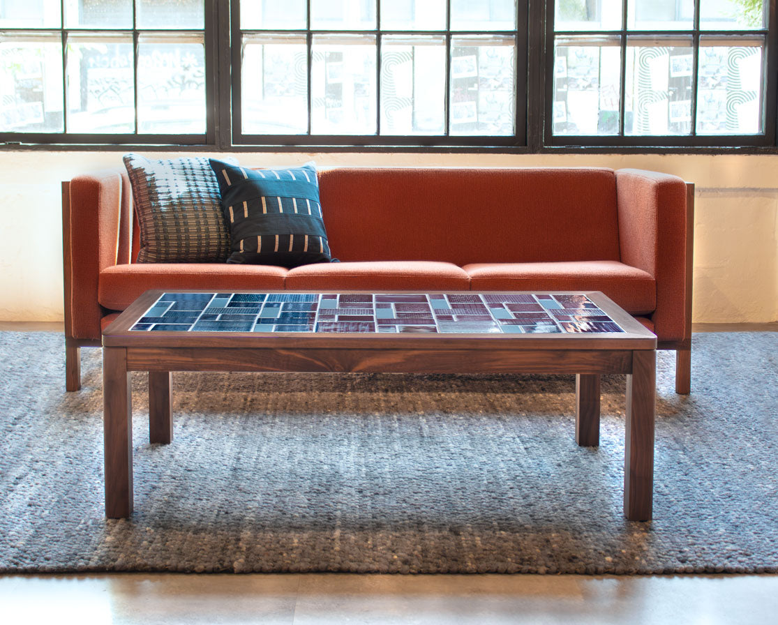 Brown leather sofa with patterned cushions in a room with large windows.