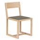 A minimalist wooden dining chair with a light natural oak frame and a textured dark gray fabric seat cushion, shown against a plain white background.