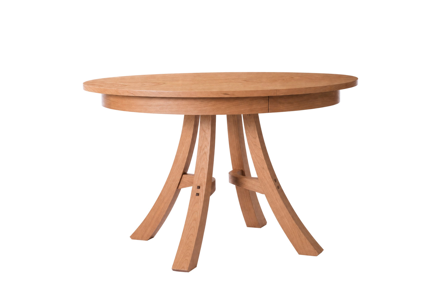 A round wooden dining table with a natural oak finish, featuring a thick oval tabletop and three curved splayed legs connected by a central stretcher, shown on a plain white background.