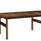 A dark brown wooden dining table with a rectangular top, visible wood grain, and four legs with stretcher supports, shown on a plain white background.