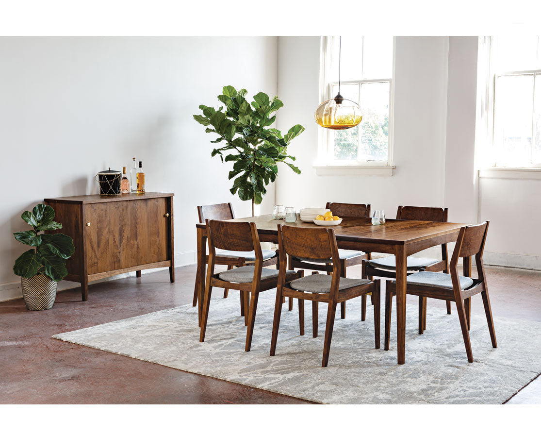 Dining room with wooden furniture including a table and chairs, sideboard, and plants.