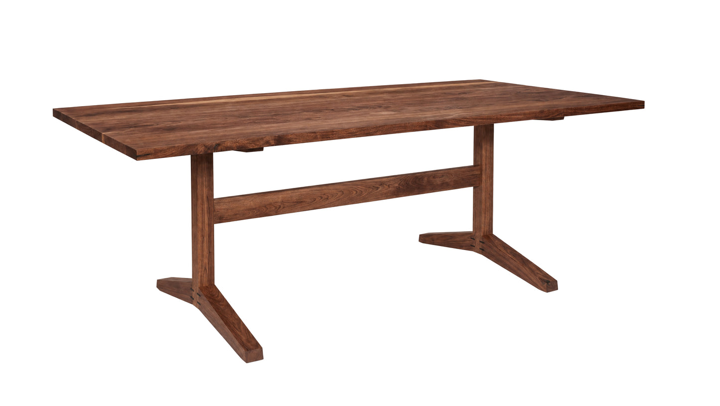 A rectangular wooden dining table with a medium-to-dark brown finish, featuring a thick apron base and angled A-shaped legs, shown on a plain white background.