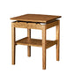 A wooden side table with a warm medium-brown finish, features a lower shelf, and walnut risers under the tabletop, set against a plain white background.