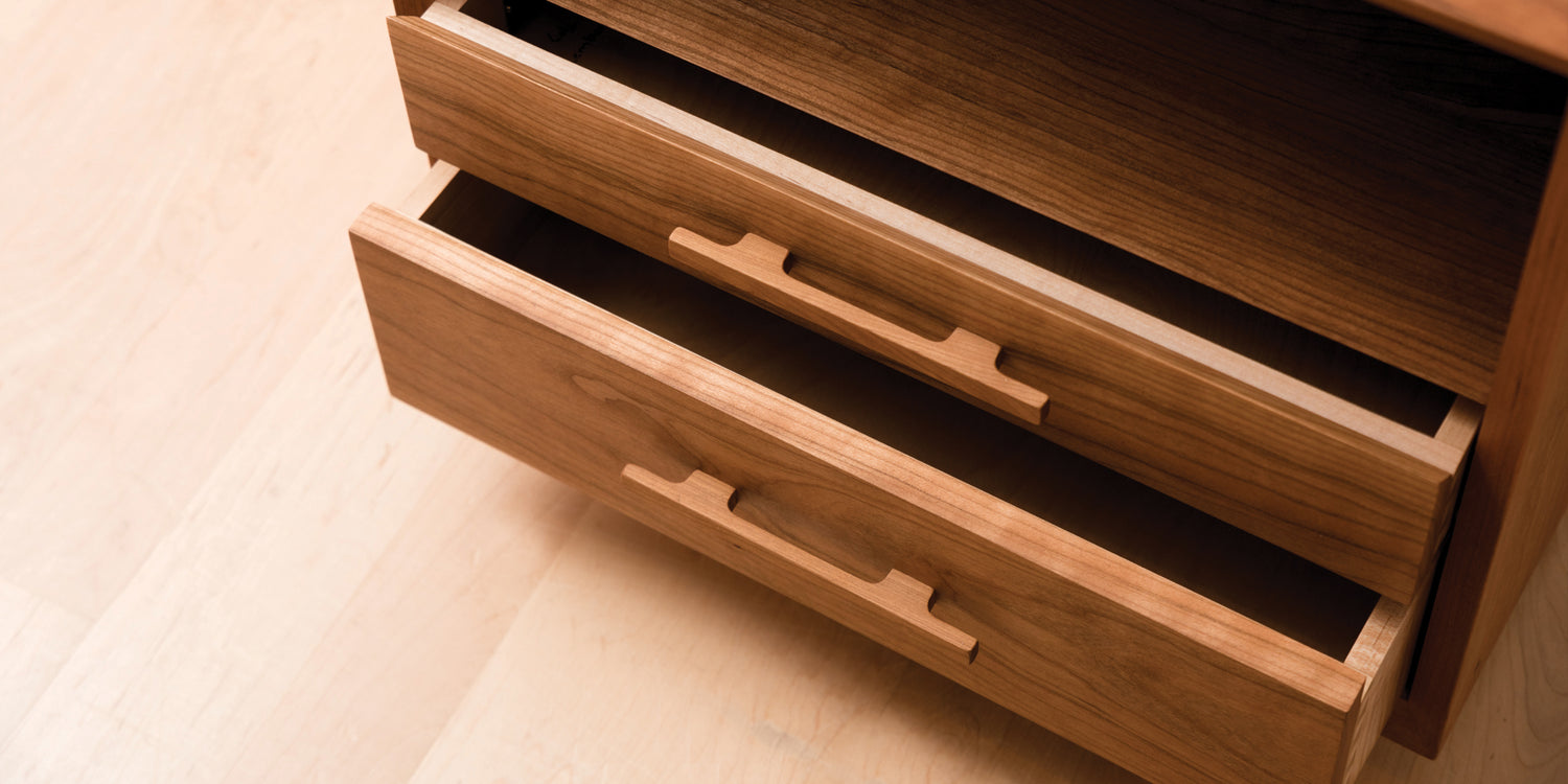 Wooden dresser with open drawer on a light wooden floor