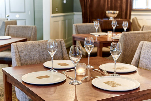 Dining table set with wine glasses, plates, and candles in a restaurant setting.
