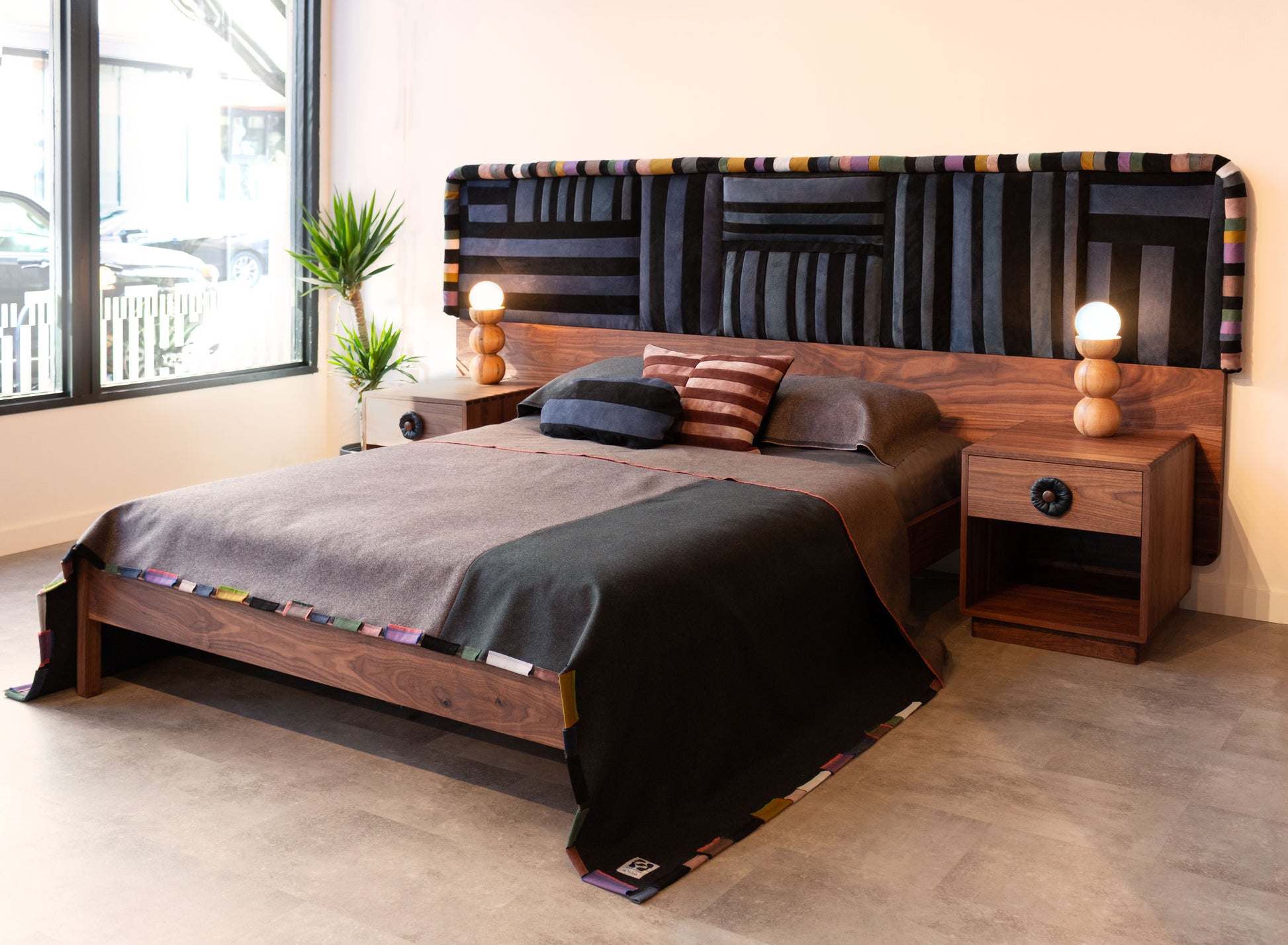 Bedroom with wooden bed and nightstands, colorful headboard, and decorative pillows.