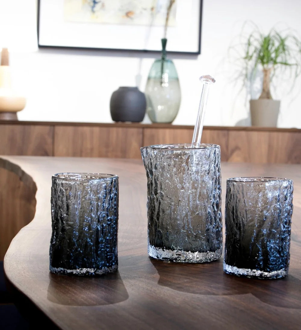 Set of three textured glass tumblers on a wooden surface with a blurred indoor background.