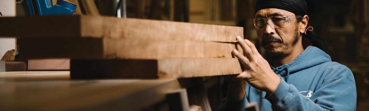 Man in a workshop examining wooden planks